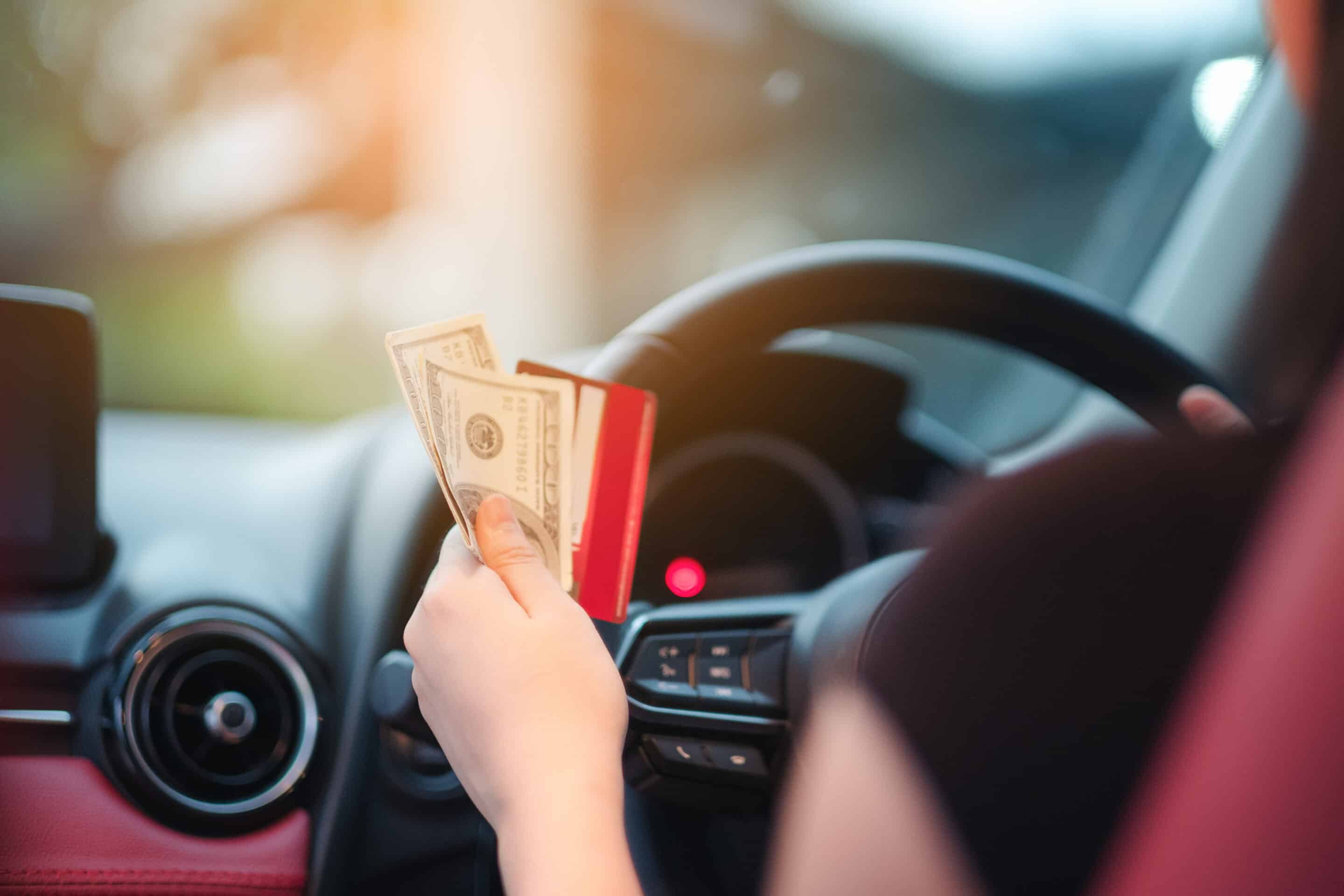 Woman in car holding cash and a card